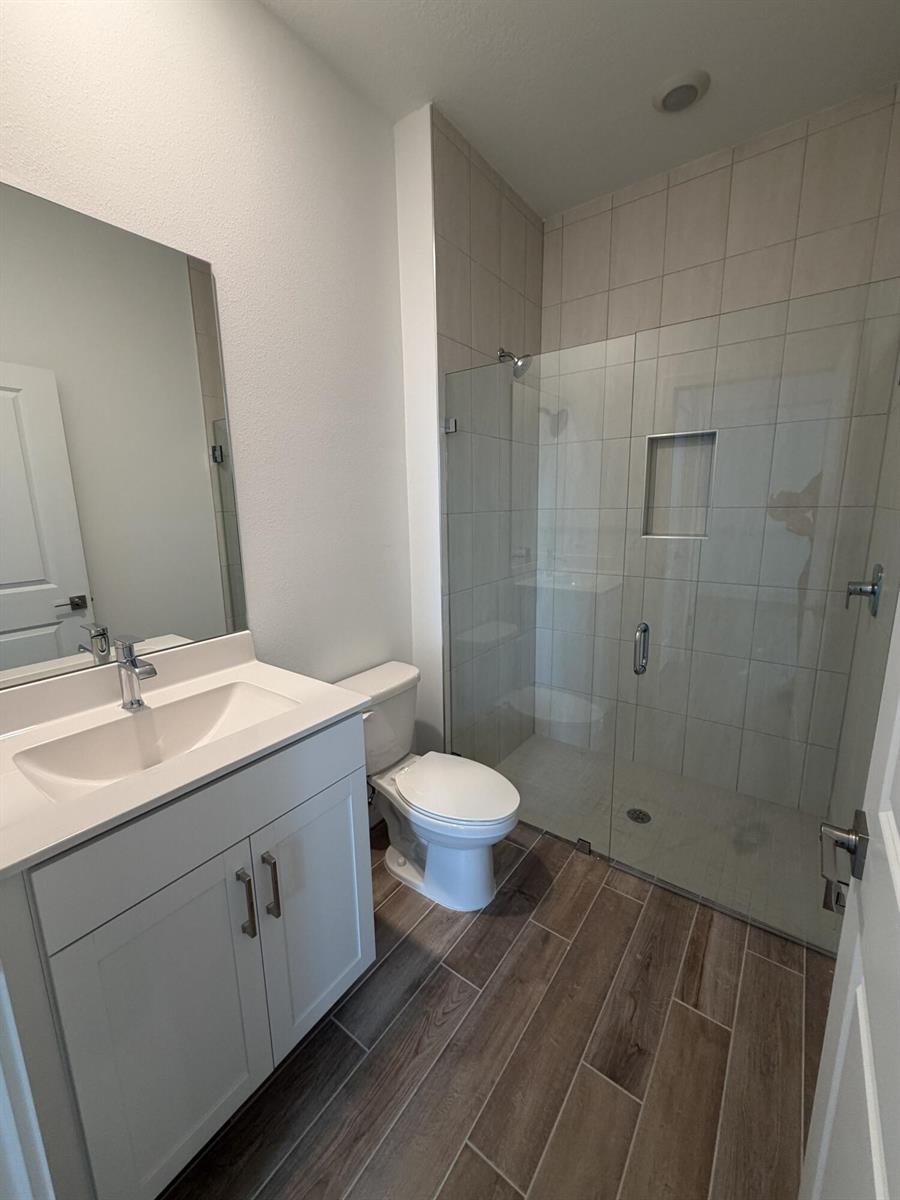 A bathroom features a white vanity, a toilet, and a glass-enclosed walk-in shower — 6781 SE Park Trace Drive, Stuart FL 34997, STUART, FL