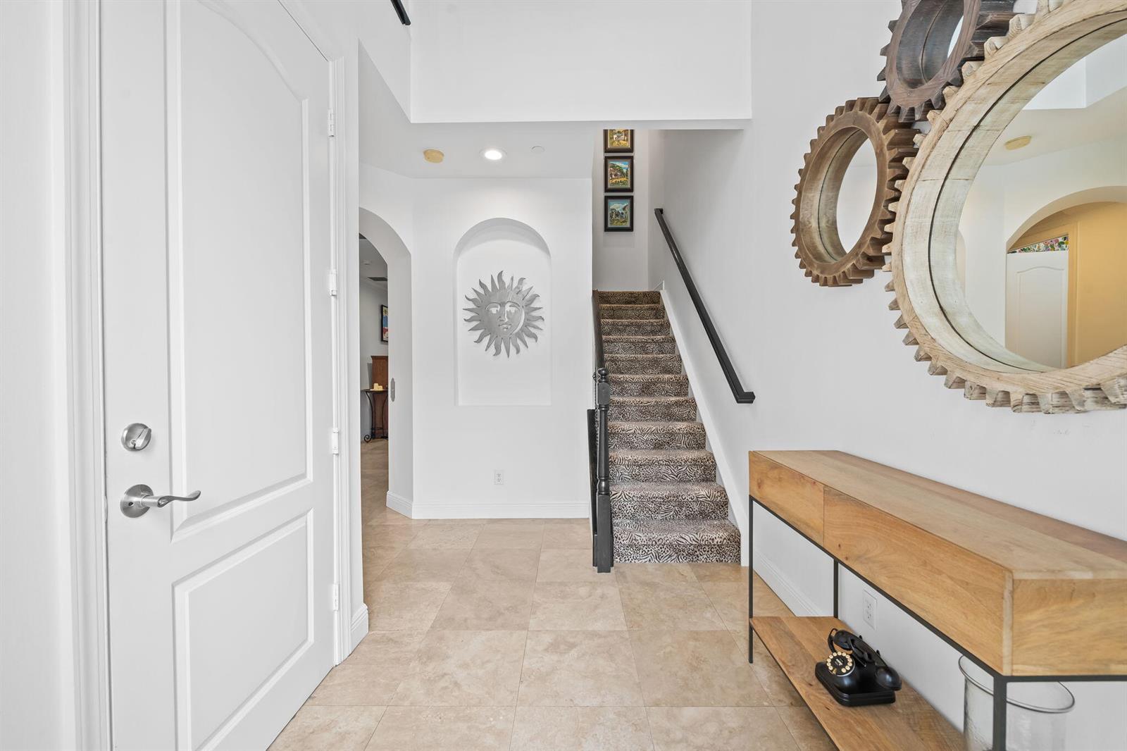 A bright entryway features tile flooring, a staircase with patterned carpet, and a wooden console — 5580 NE Trieste Terrace, Boca Raton FL 33487, BOCA RATON, FL