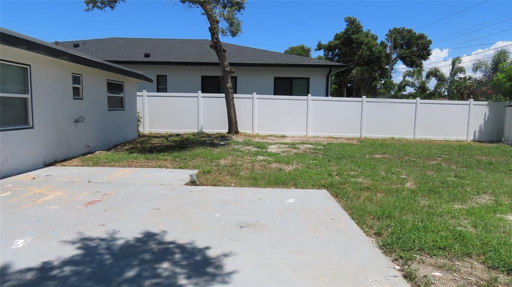 A concrete patio sits adjacent to a white house with a fenced backyard and tree — 4594 17TH AVENUE N, ST PETERSBURG, FL