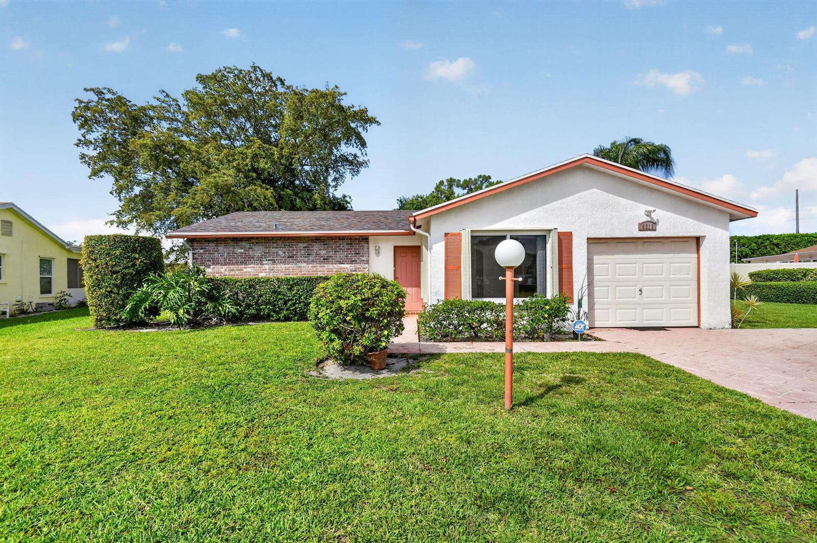 A single-story house with a brick and white exterior, a garage, and a front lawn — 6312 Summer Sky Lane, FL 33463, FL