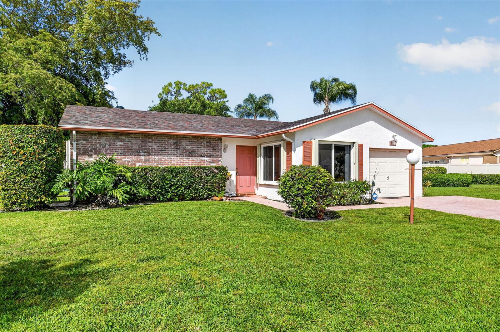 A single-story house with a brick and white exterior, a pink door, and a garage — 6312 Summer Sky Lane, FL 33463, FL