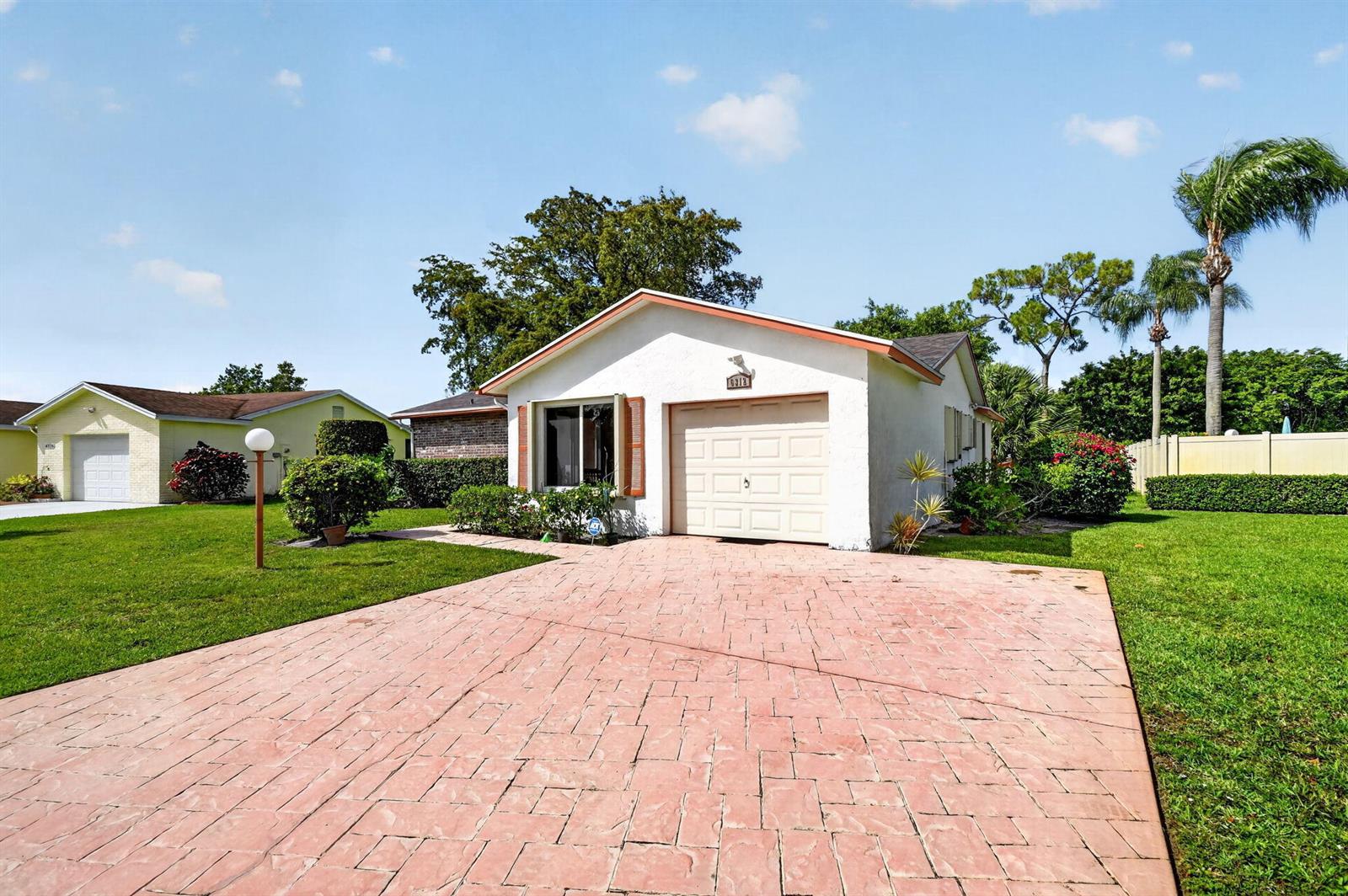 A single-story house with a white exterior, a garage, and a stamped concrete driveway — 6312 Summer Sky Lane, FL 33463, FL