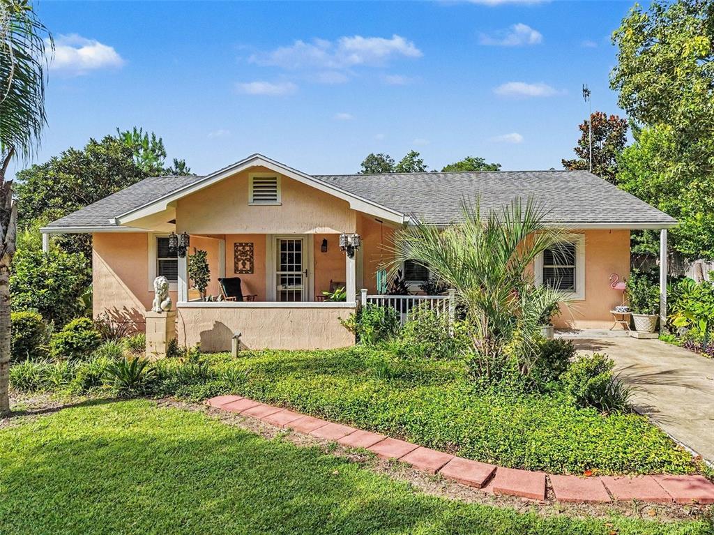 A single-story peach-colored house with a front porch, a shingled roof, and a landscaped yard — 7480 E HIGHWAY 25, BELLEVIEW, FL