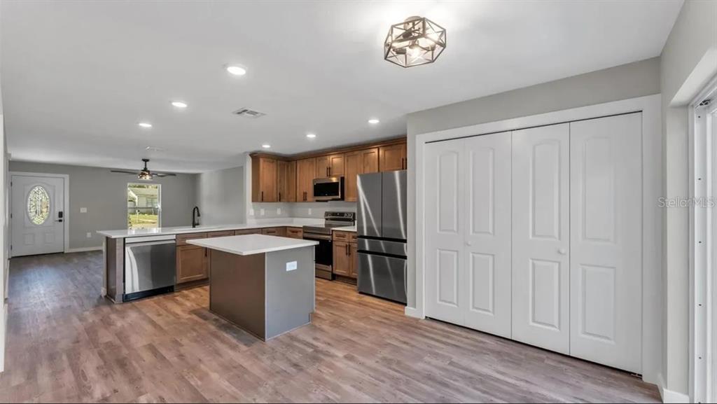 A kitchen features wood cabinets, stainless steel appliances, a center island, and white closet doors — 0 38TH STREET NW, WINTER HAVEN, FL