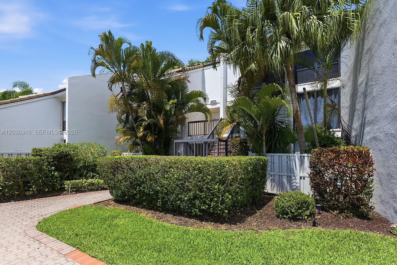 A two-story residential building features a paved walkway, manicured hedges, and tall palm trees — 1309 Bridgewood Dr, Boca Raton FL 33434, BOCA RATON, FL