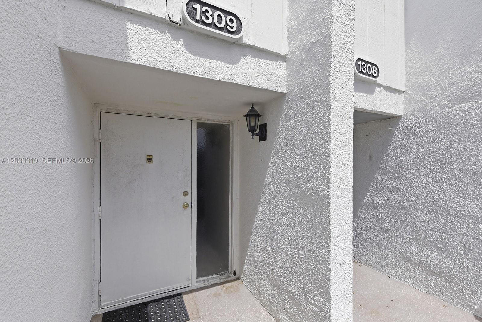 The exterior view shows two white stucco residential entryways labeled 1309 and 1308 — 1309 Bridgewood Dr, Boca Raton FL 33434, BOCA RATON, FL