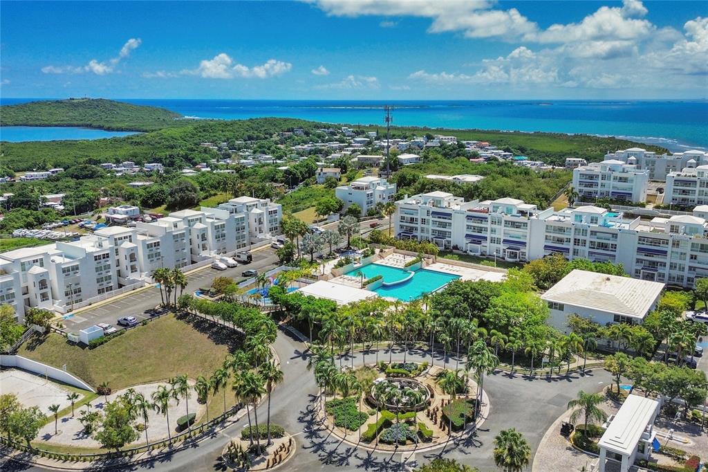 An aerial view shows a residential complex with a swimming pool, palm trees, and ocean — 200 OCEAN CLUB AT SEVEN SEAS UNIT DC-402, FAJARDO, PR