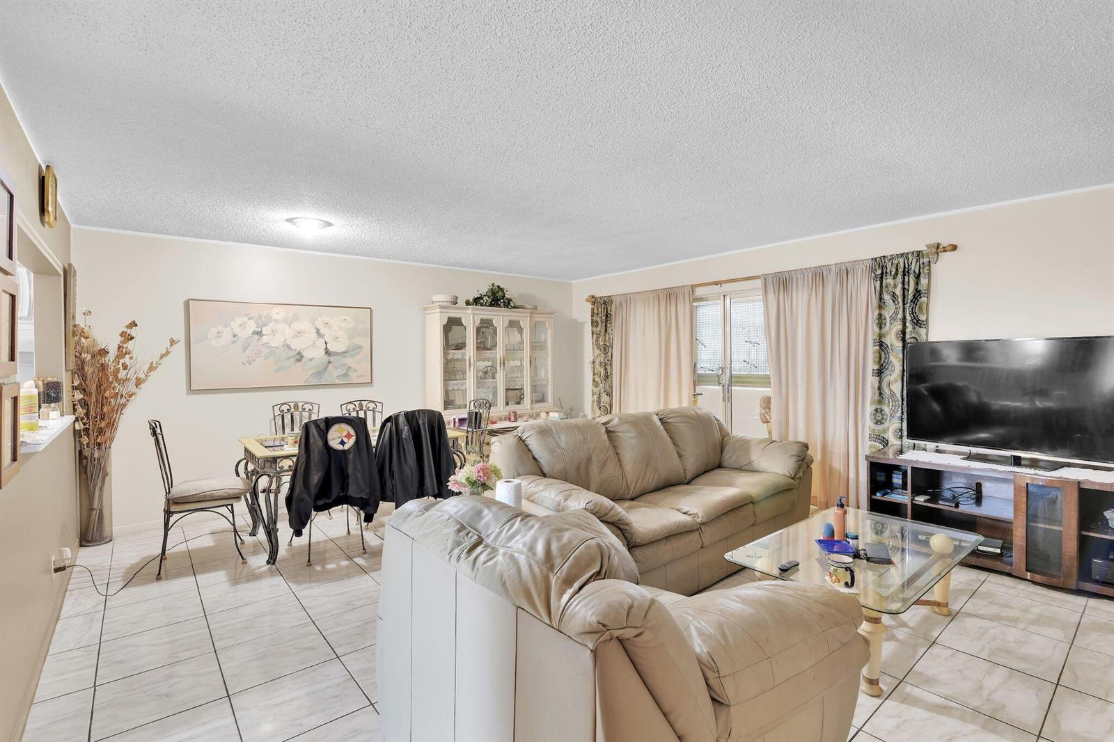 A living and dining room with tile floors, a beige sofa, and a glass coffee table — 711 Lori Drive # 204, Palm Springs FL 33461, PALM SPRINGS, FL