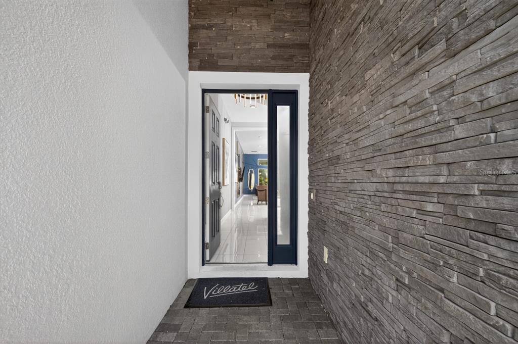 A front entryway features a stone-clad wall, a dark door, and a tiled floor — 1735 OAK BLOSSOM DRIVE, DAVENPORT, FL