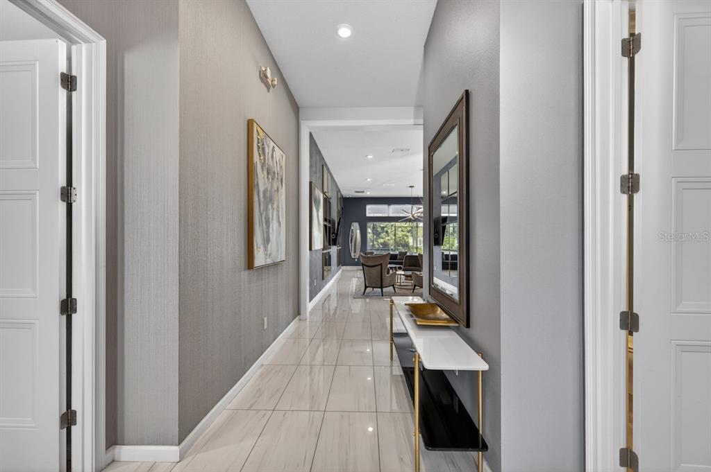 A long hallway with light tile flooring leads toward a bright living area — 1735 OAK BLOSSOM DRIVE, DAVENPORT, FL
