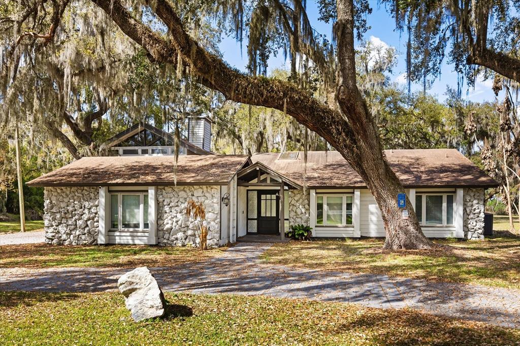 A single-story house with a stone facade and a large oak tree in the front — 1775 HARBOR ROAD, KISSIMMEE, FL