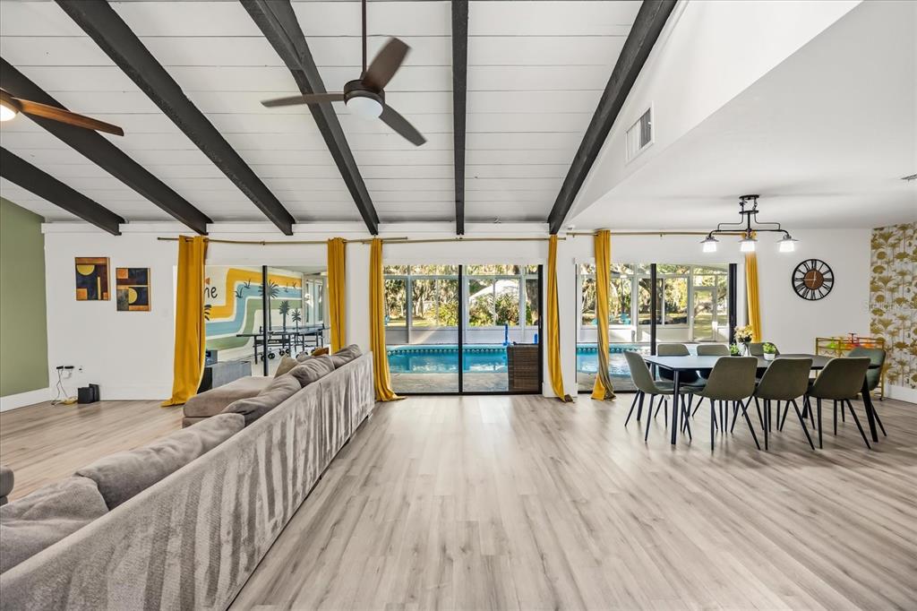 A spacious living and dining area features vaulted ceilings, exposed beams, and sliding glass doors — 1775 HARBOR ROAD, KISSIMMEE, FL