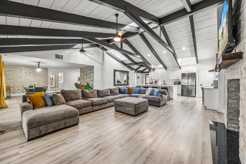 A large open-concept living room features vaulted ceilings with exposed beams and wood flooring — 1775 HARBOR ROAD, KISSIMMEE, FL