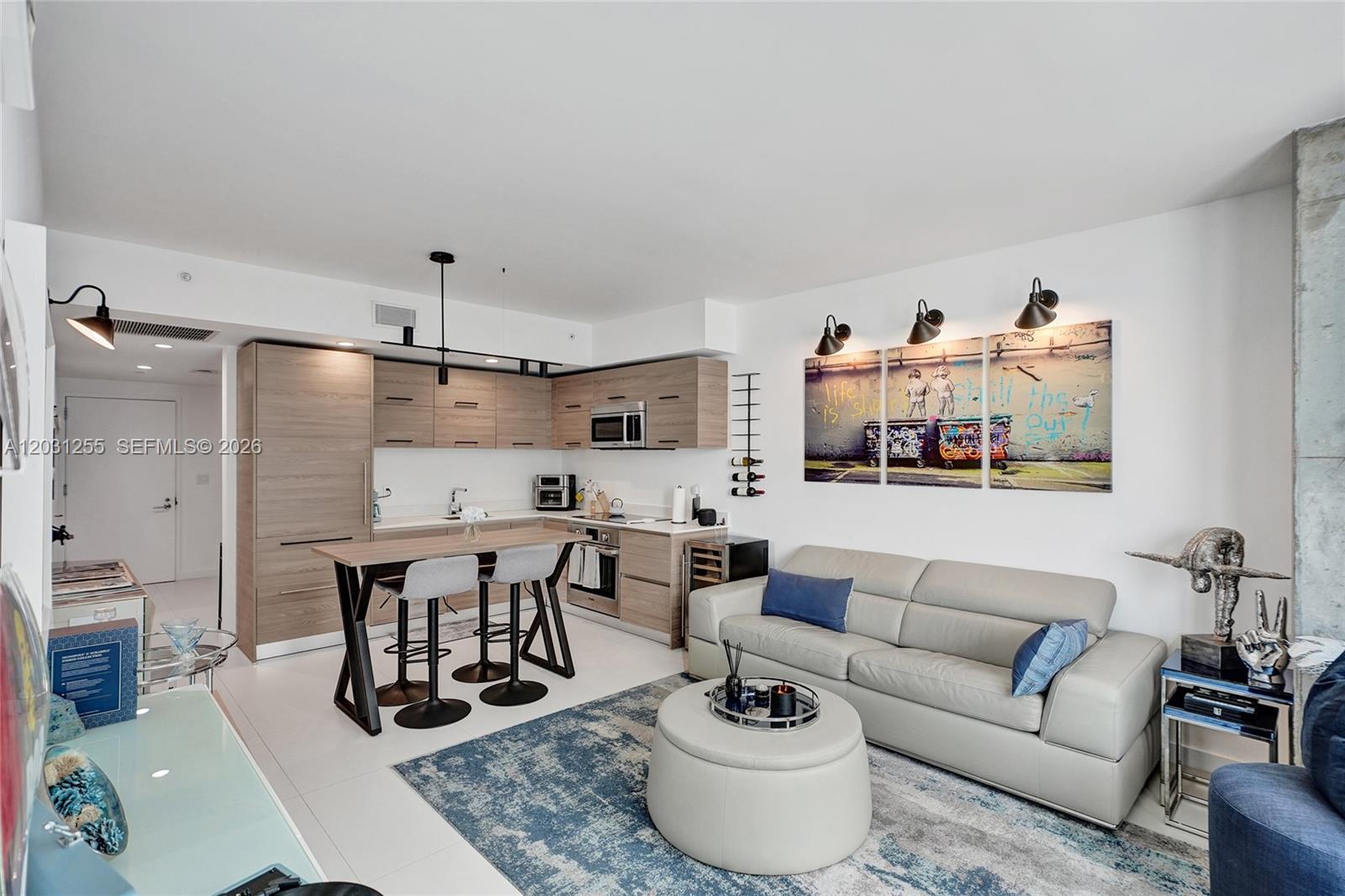A modern kitchen and living area featuring light wood cabinetry, a breakfast bar, and sofa — 1300 S Miami Ave # 4508, Miami FL 33130, MIAMI, FL
