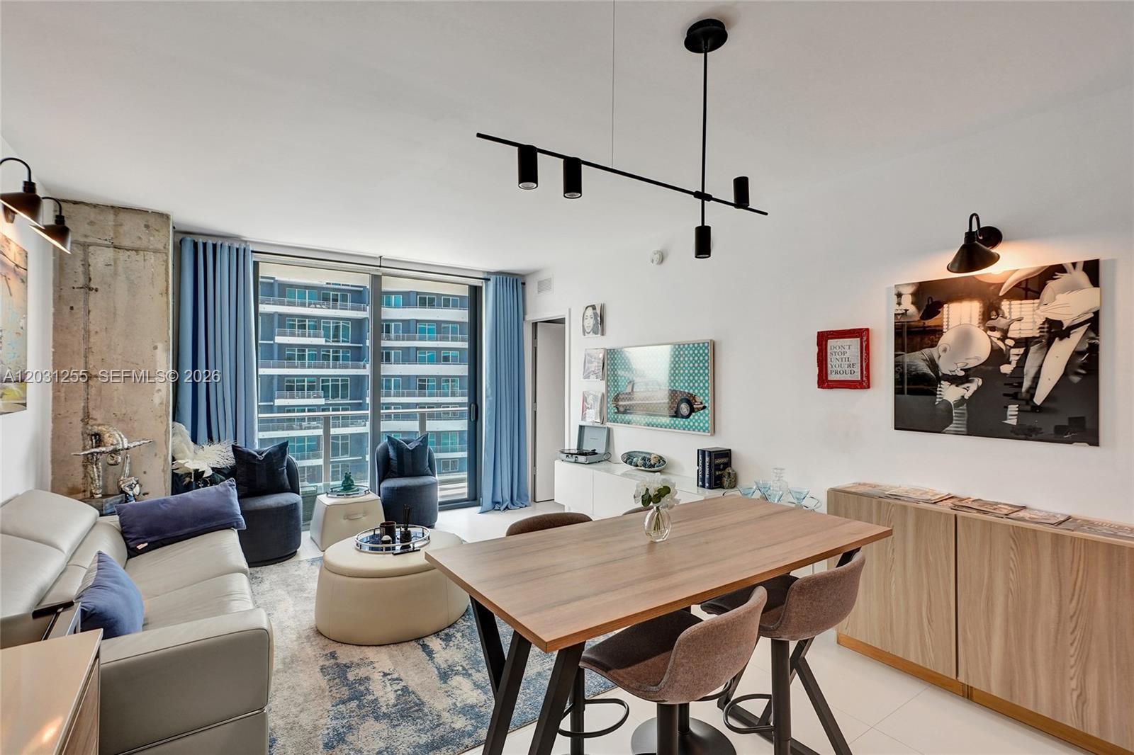 A modern living and dining area features a white sofa, wooden table, and balcony view — 1300 S Miami Ave # 4508, Miami FL 33130, MIAMI, FL