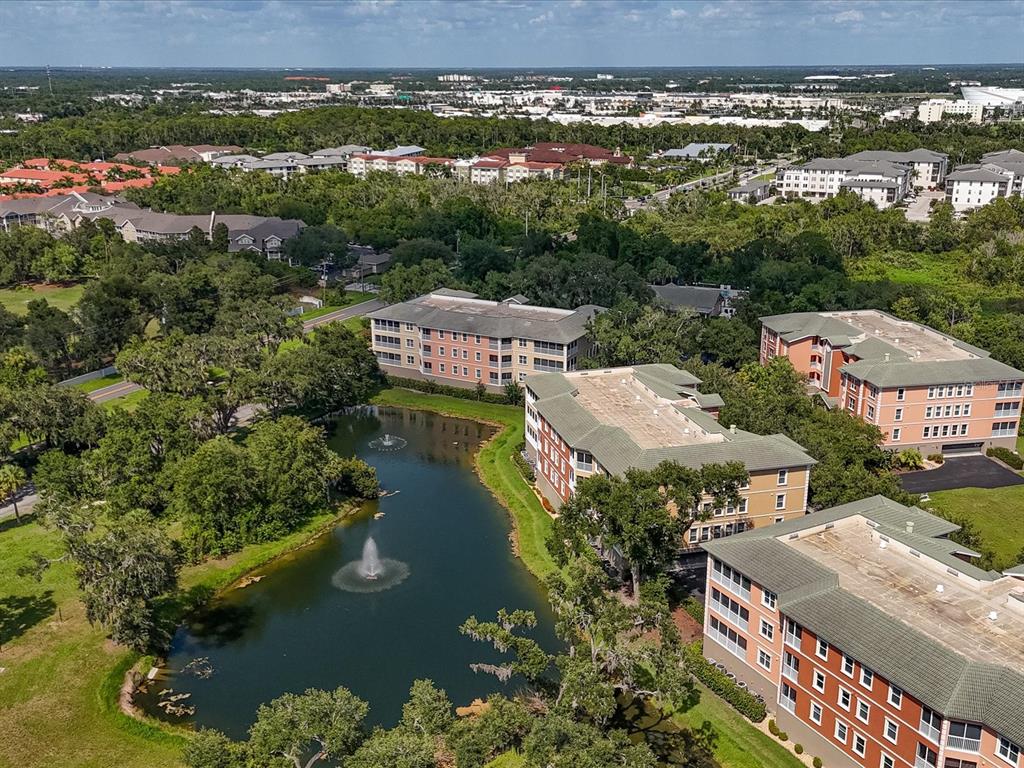 An aerial view shows several multi-story apartment buildings surrounding a pond with two fountains — 5122 MANORWOOD DRIVE UNIT 4B, SARASOTA, FL