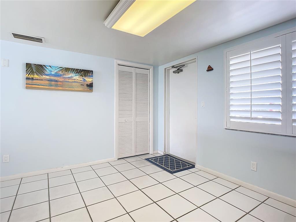 A room with light blue walls, white tile flooring, a louvered closet, and a door — 3663 S ATLANTIC AVENUE UNIT 20C, NEW SMYRNA BEACH, FL