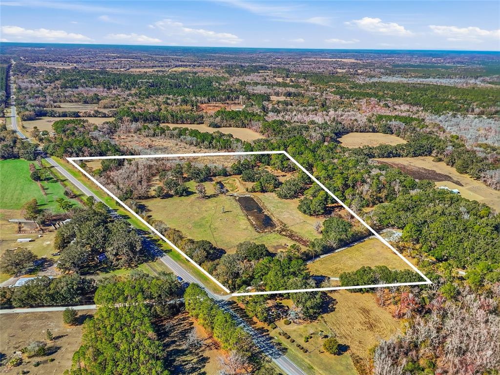 An aerial view shows a large, rectangular plot of land featuring a pond and trees — 6721 W STATE ROAD 235, ALACHUA, FL