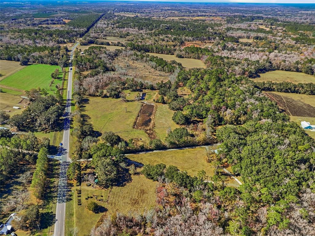 An aerial view shows a rural property with a road, open fields, and wooded areas — 6721 W STATE ROAD 235, ALACHUA, FL