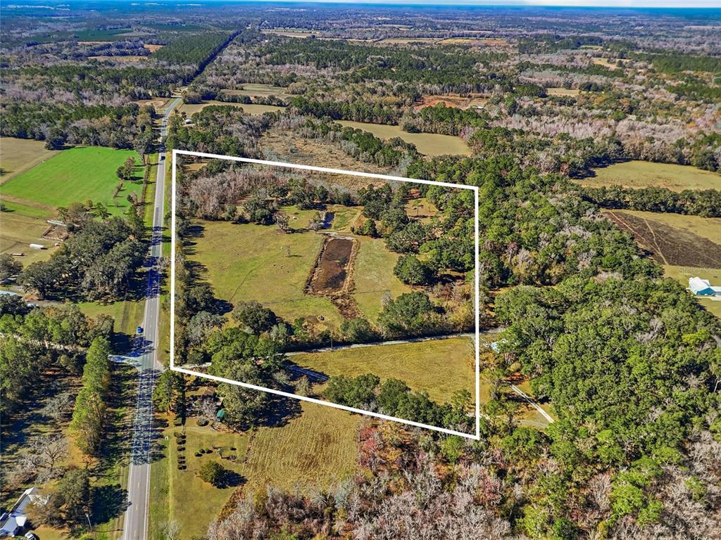 An aerial view shows a rectangular plot of land featuring a pond and pasture — 6721 W STATE ROAD 235, ALACHUA, FL