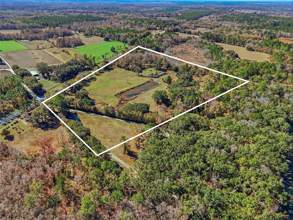 An aerial view shows a rural property with a pond and trees outlined in white — 6721 W STATE ROAD 235, ALACHUA, FL