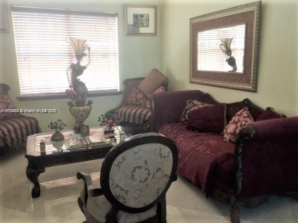 A living room features a dark wood coffee table, a patterned sofa, and an armchair — 4854 NW 110th Pl, Doral FL 33178, DORAL, FL