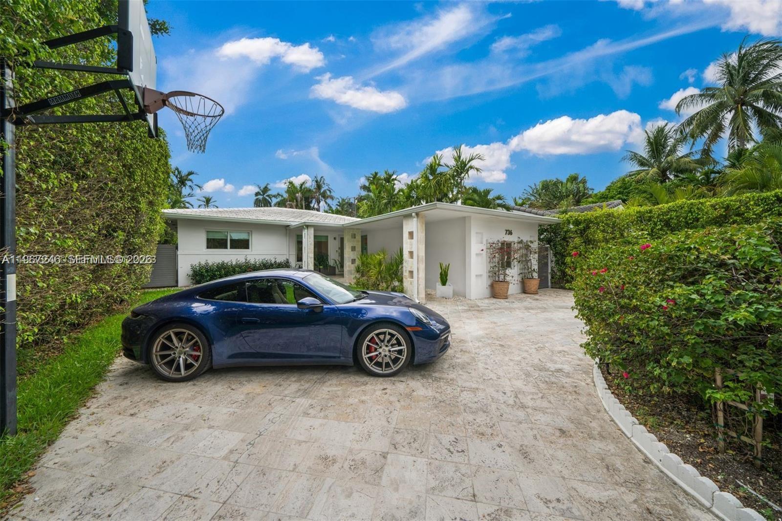 A blue sports car is parked on a stone driveway next to a white house — 736 W 51 st, Miami Beach FL 33140, MIAMI BEACH, FL