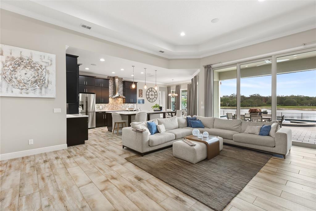 An open-concept living room and kitchen feature tile flooring, dark cabinetry, and large sliding glass doors — 3967 EQUINE COVE, LAKE MARY, FL