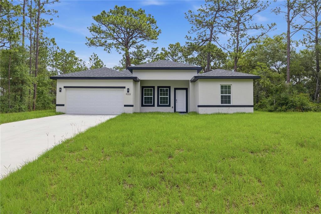 A single-story house with a white exterior, dark trim, and a concrete driveway — 9333 N SAMOA WAY, CITRUS SPRINGS, FL