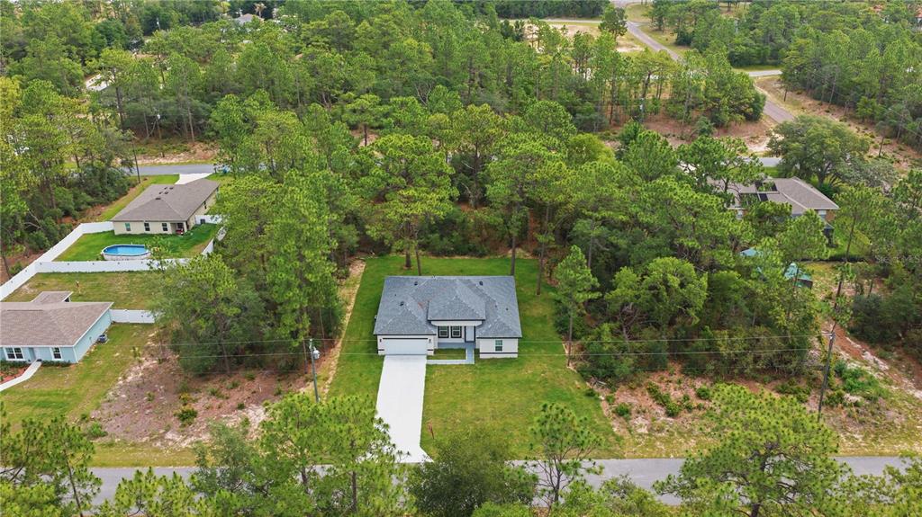 An aerial view shows a single-story house with a gray roof surrounded by pine trees — 9333 N SAMOA WAY, CITRUS SPRINGS, FL