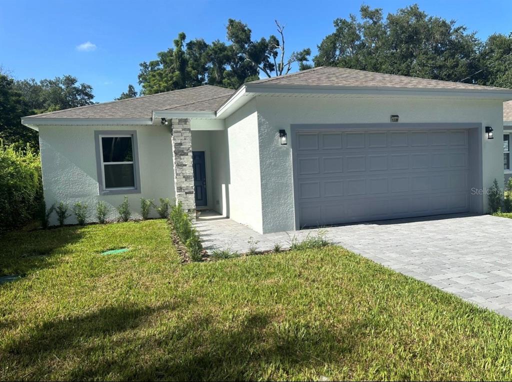 A single-story house with white stucco walls, a gray garage door, and a stone-accented entryway — 1226 36TH STREET, ORLANDO, FL