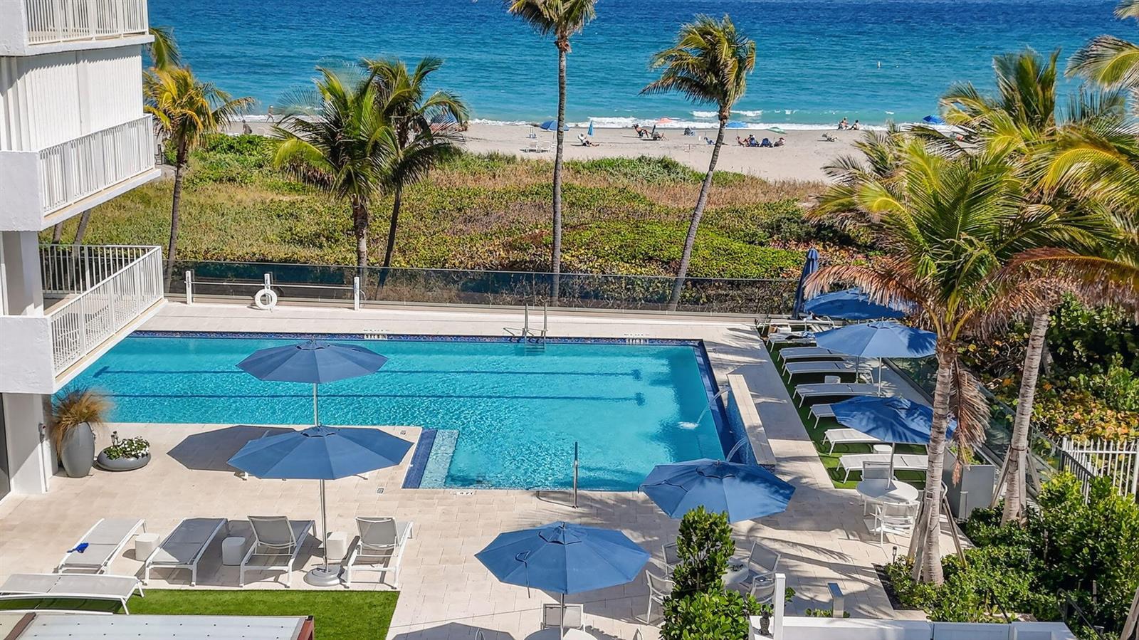 An elevated view of a swimming pool with lounge chairs and umbrellas overlooking the beach — 3000 S Ocean Boulevard # 1004, Boca Raton FL 33432, BOCA RATON, FL