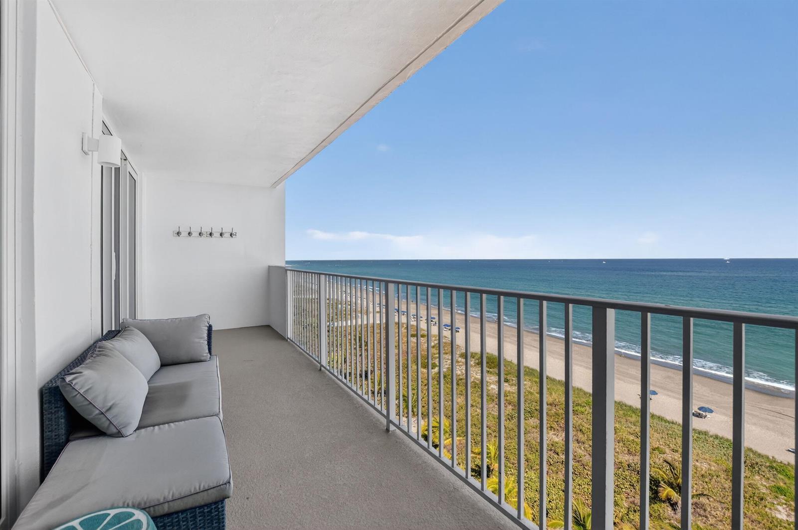 A balcony with a gray sofa overlooks a sandy beach and the ocean — 3000 S Ocean Boulevard # 1004, Boca Raton FL 33432, BOCA RATON, FL