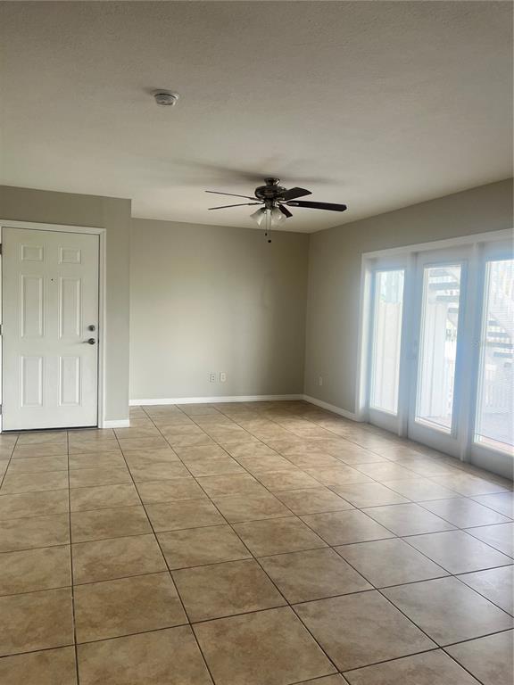 An empty room features light-colored tile flooring, a ceiling fan, and a white entry door — 4728 BEACH DRIVE SE UNIT B, ST PETERSBURG, FL