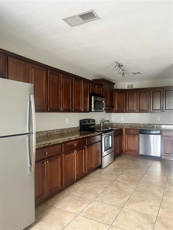 A kitchen features dark wood cabinets, granite countertops, and stainless steel appliances — 4728 BEACH DRIVE SE UNIT B, ST PETERSBURG, FL