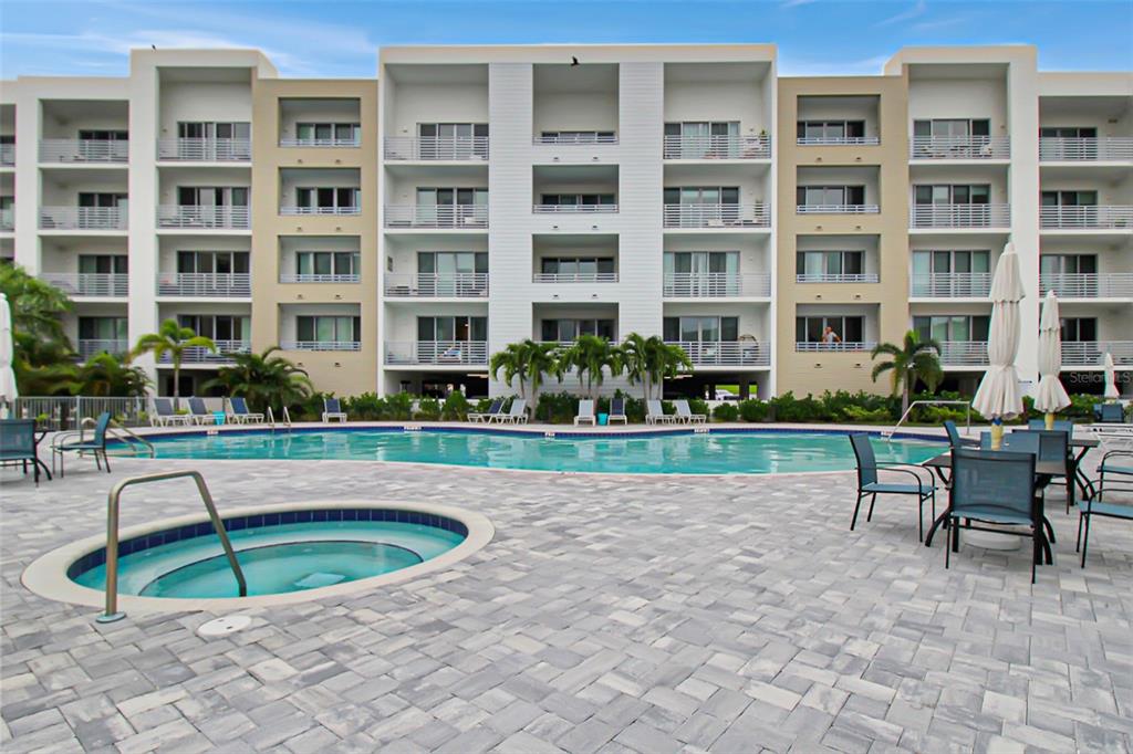 A multi-story apartment building overlooks a swimming pool and a circular hot tub — 1703 N TAMIAMI TRAIL UNIT 503, SARASOTA, FL