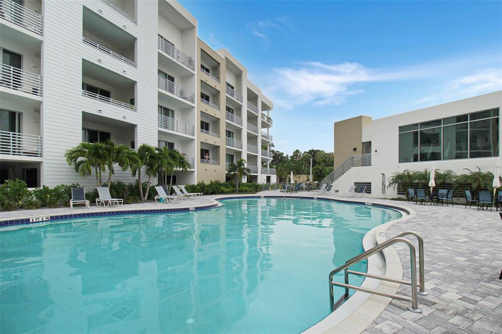 A swimming pool sits in front of a multi-story apartment building with balconies — 1703 N TAMIAMI TRAIL UNIT 503, SARASOTA, FL