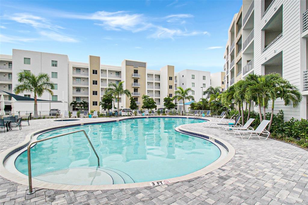 A swimming pool with lounge chairs sits in the courtyard of a modern apartment complex — 1703 N TAMIAMI TRAIL UNIT 503, SARASOTA, FL