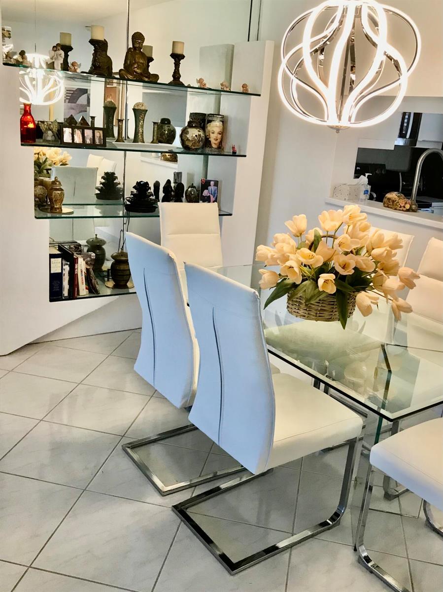 A dining room features a glass table, white chairs, and a mirrored display shelf — 1025 SE 4th Avenue # 101, Dania Beach FL 33004, DANIA BEACH, FL