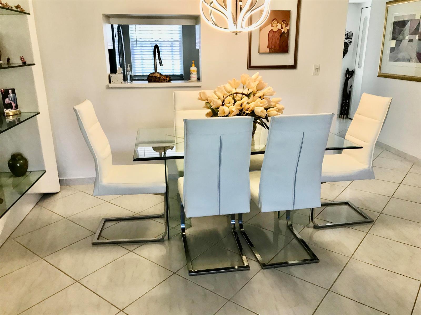 A dining room features a glass table, four white chairs, and a modern light fixture — 1025 SE 4th Avenue # 101, Dania Beach FL 33004, DANIA BEACH, FL