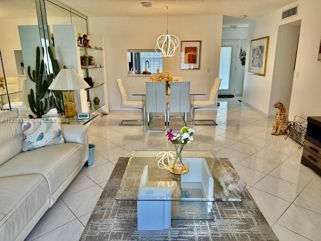 A bright living and dining area features white tile floors, modern furniture, and a glass table — 1025 SE 4th Avenue # 101, Dania Beach FL 33004, DANIA BEACH, FL