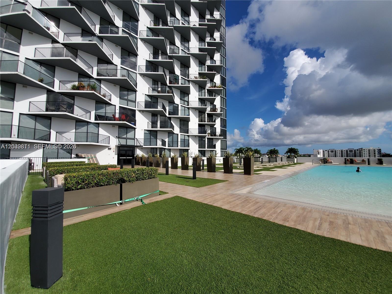 A modern high-rise building features a rooftop pool deck with artificial turf and planters — 5252 NW 85th Ave # 1504, Doral FL 33166, DORAL, FL