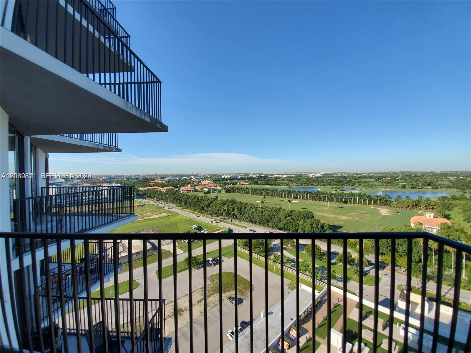 A high-angle view from a balcony overlooking a golf course, parking lot, and road — 5252 NW 85th Ave # 1504, Doral FL 33166, DORAL, FL