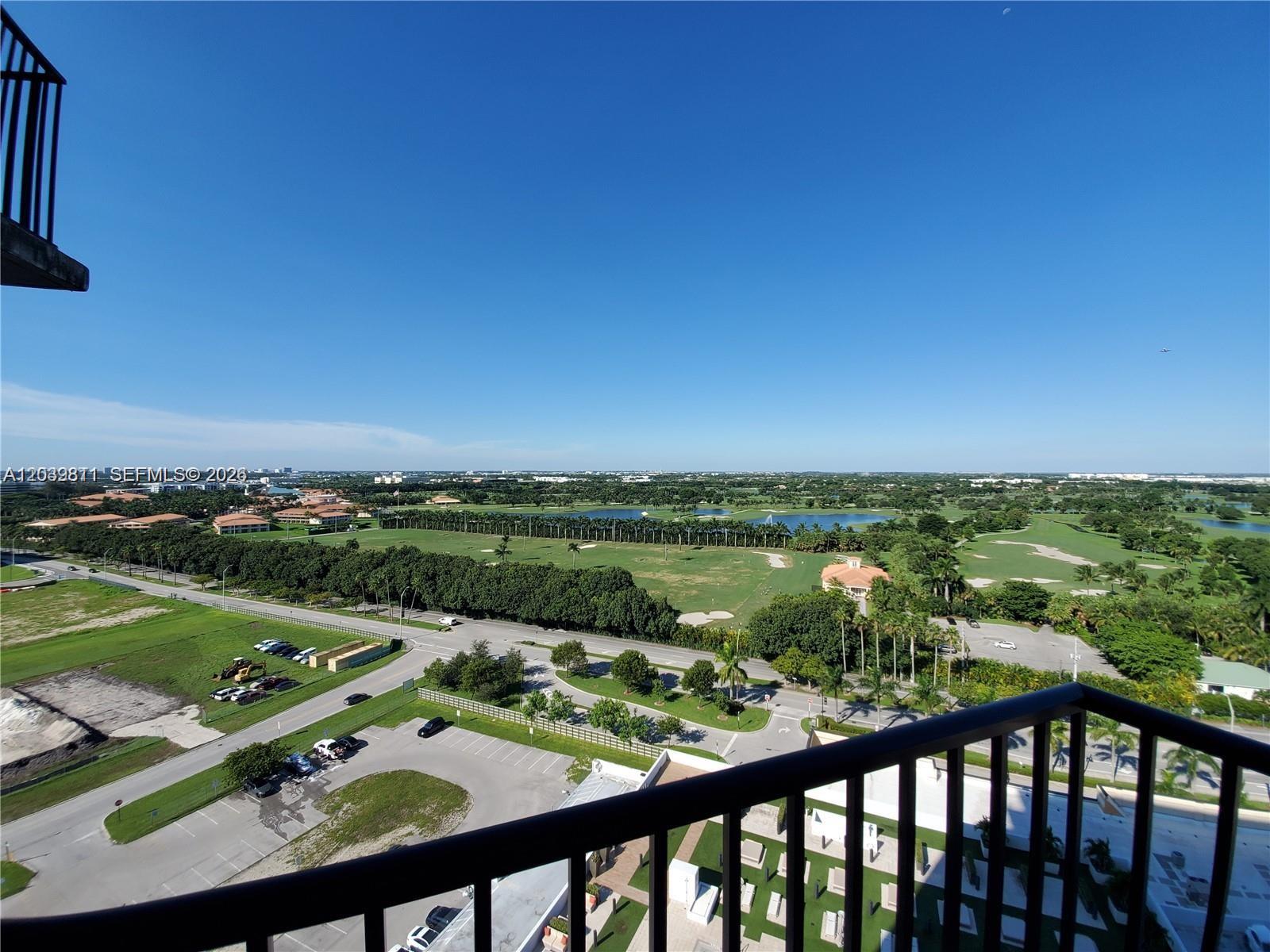 A high-angle view from a balcony overlooks a golf course, parking lot, and road — 5252 NW 85th Ave # 1504, Doral FL 33166, DORAL, FL