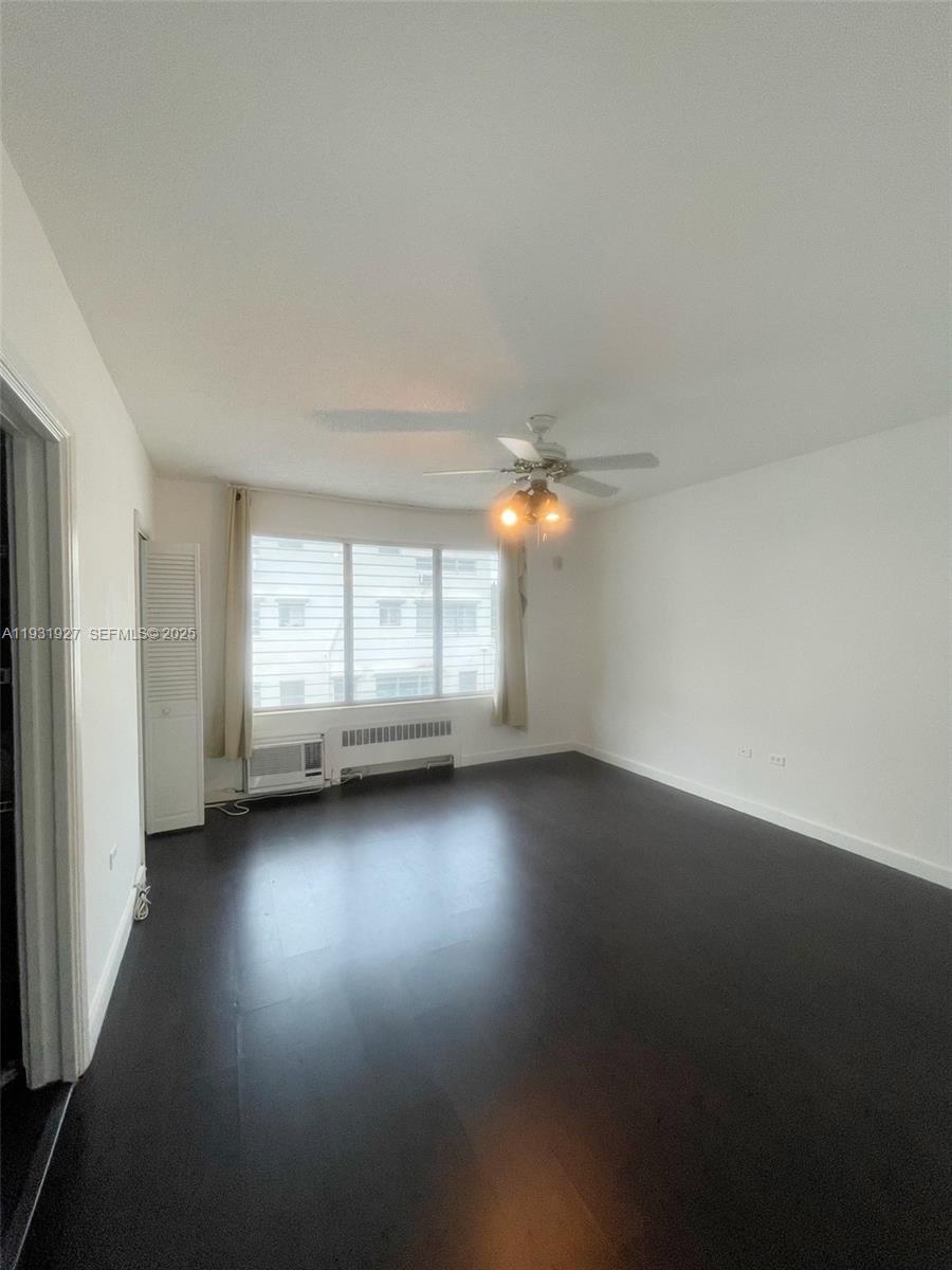 An empty room features dark wood flooring, a ceiling fan, and a large window — 10178 Collins Ave # 202, Bal Harbour FL 33154, BAL HARBOUR, FL
