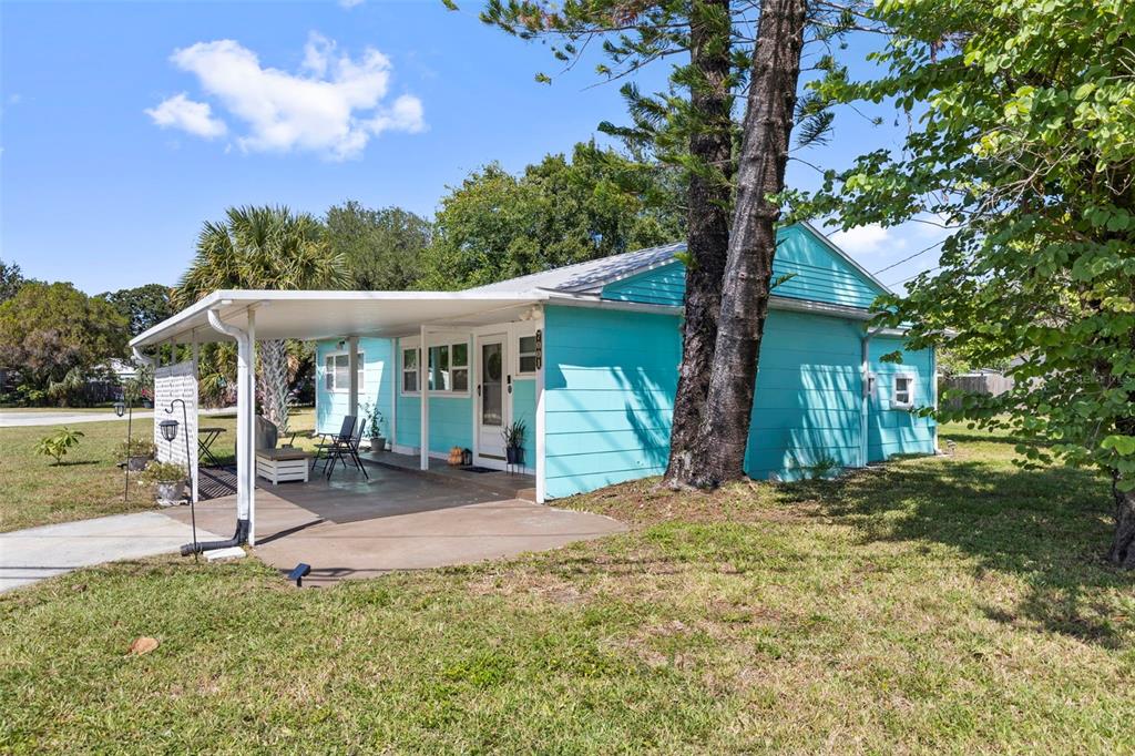 A light blue house with a covered concrete patio and a large tree in front — 7001 13TH STREET N, ST PETERSBURG, FL