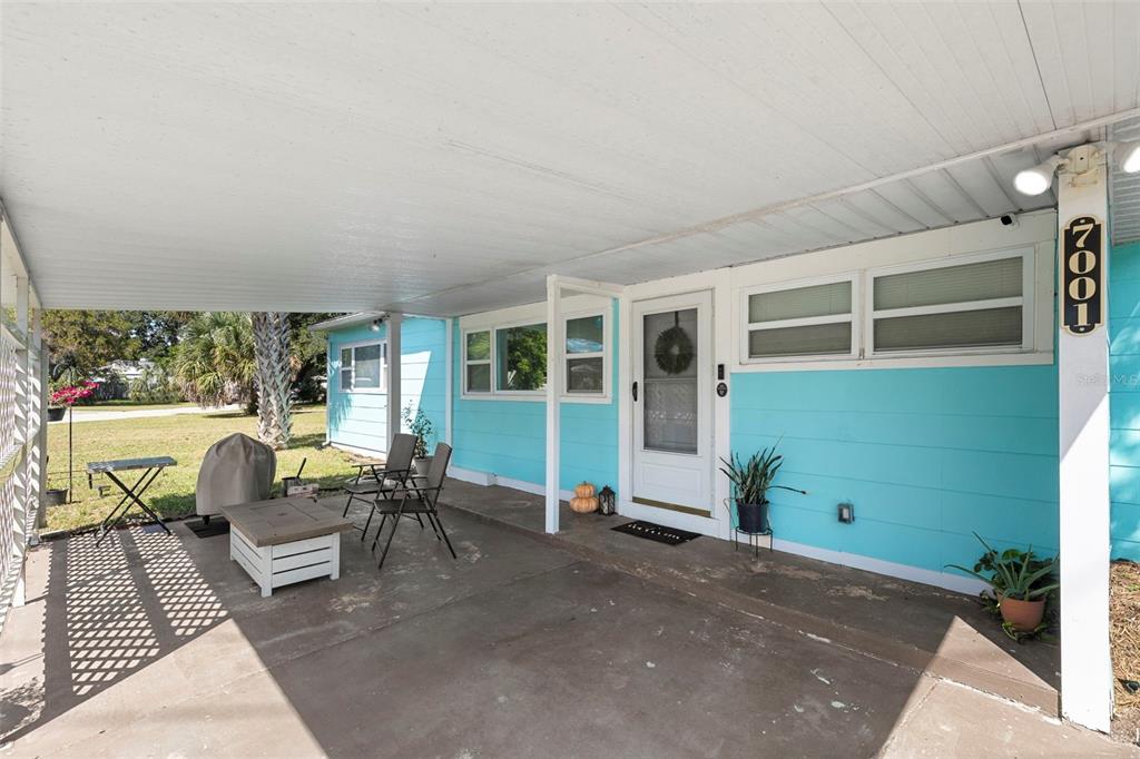 A covered concrete patio sits in front of a light blue house with white trim — 7001 13TH STREET N, ST PETERSBURG, FL