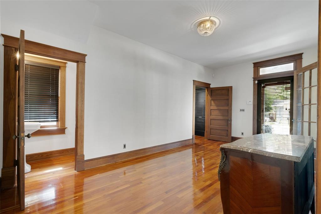 A room with hardwood floors, white walls, wood trim, and a marble-topped kitchen island — 716 E LIME STREET, LAKELAND, FL