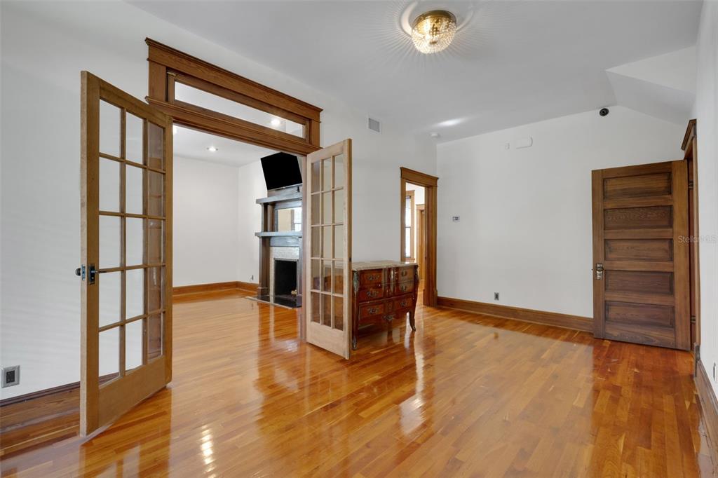 A room with hardwood floors, French doors, a fireplace, and a wooden door — 716 E LIME STREET, LAKELAND, FL