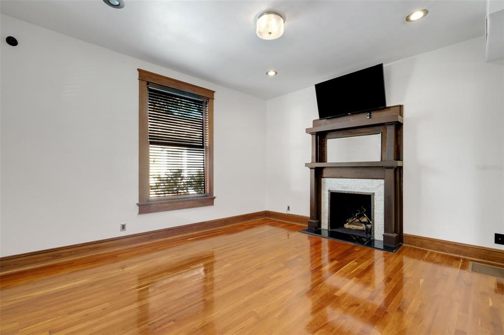 A living room features hardwood floors, a window with dark trim, and a fireplace mantel — 716 E LIME STREET, LAKELAND, FL